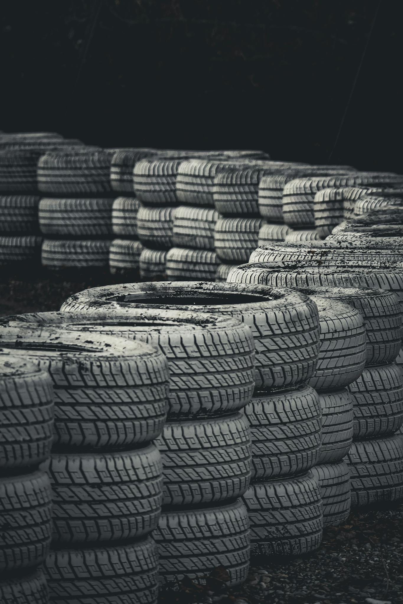 Vertical shot of stacked racing tires on a dark background for protection.